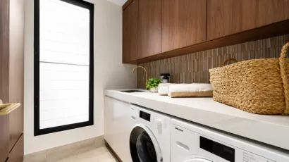 Custom laundry cabinetry with overhead storage, benchtop and integrated appliances in a Melbourne home