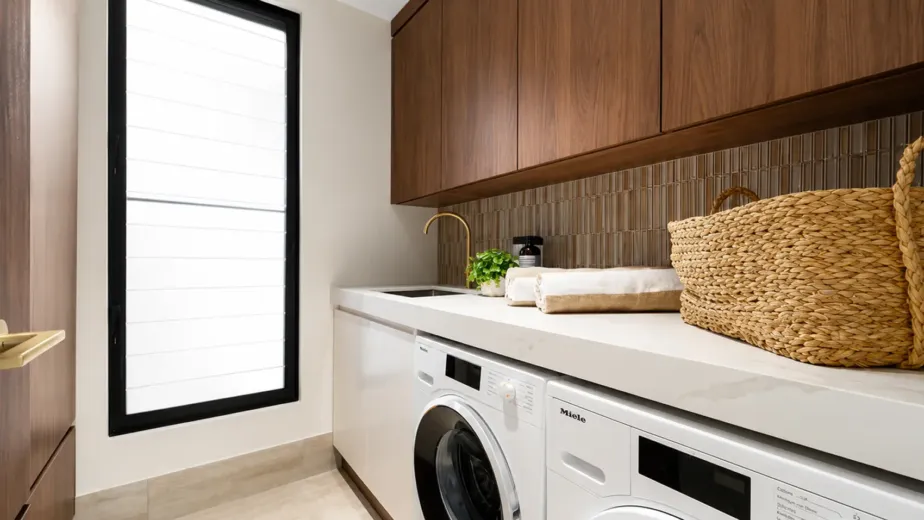 Custom laundry cabinetry with overhead storage, benchtop and integrated appliances in a Melbourne home