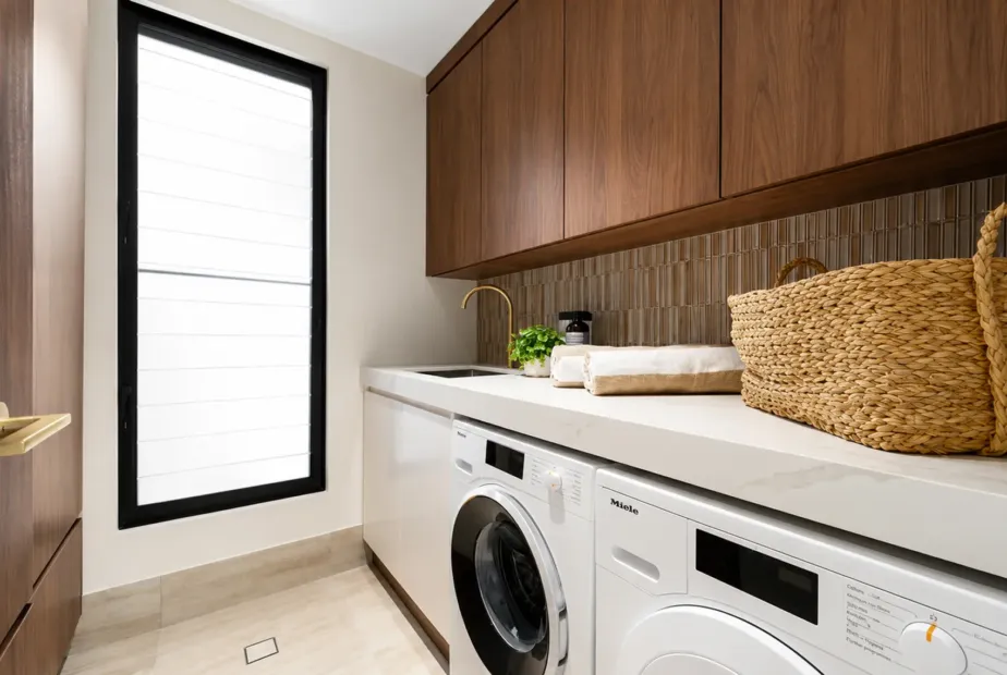 Custom laundry cabinetry with overhead storage, benchtop and integrated appliances in a Melbourne home